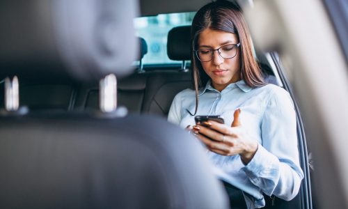 Business woman sitting in car and using phone